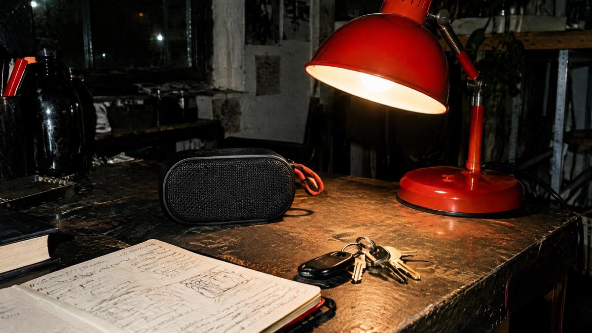 A red desk lamp over a notebook and a radio on a night desk