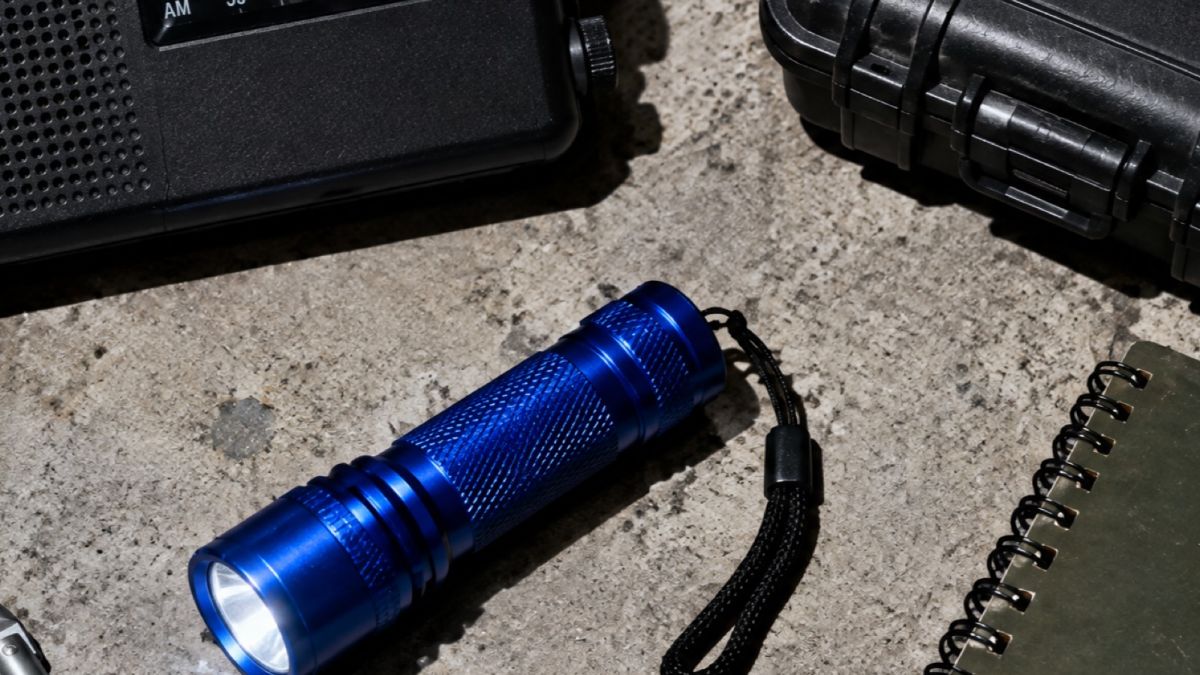 A field radio, a hard case and a flashlight on concrete
