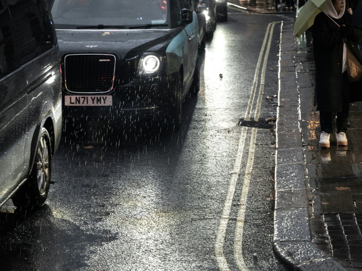 A black taxi on a wet street at night in London